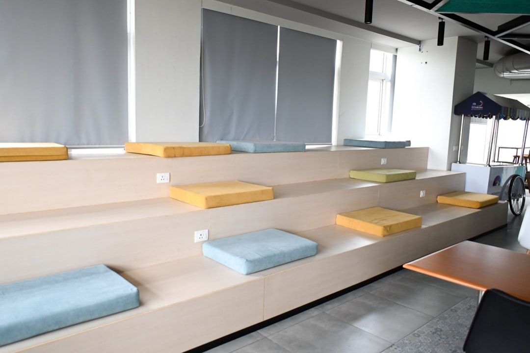 Modern sittrappa med färgglada kuddar i en coworking-lounge.