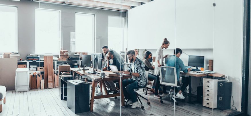 Människor arbetar vid delade skrivbord på ett modernt kontorshotell i Stockholm.