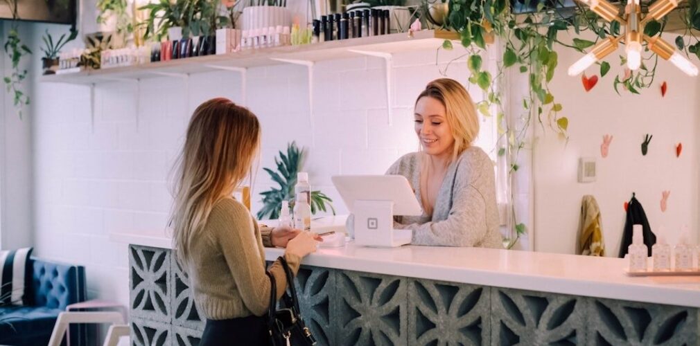 Hotellreceptionist tar emot gäst vid en disk med laptop