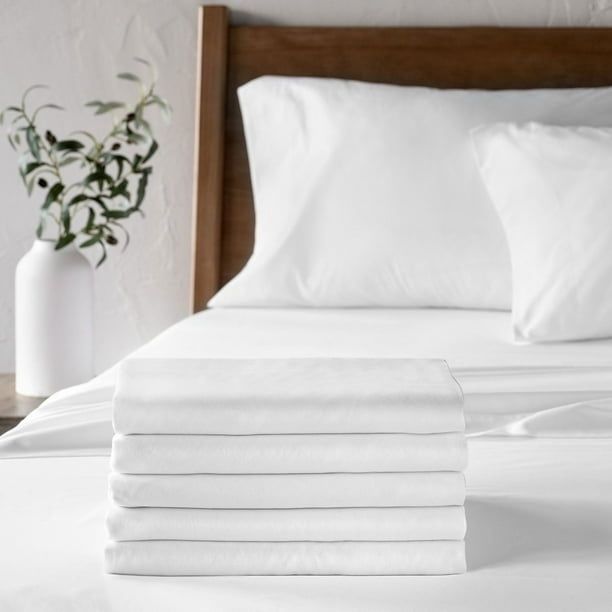Stapel med vikta vita lakan på en bäddad hotellsäng